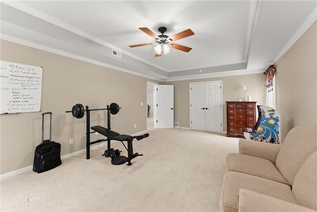 workout room featuring ceiling fan, a raised ceiling, carpet floors, and ornamental molding