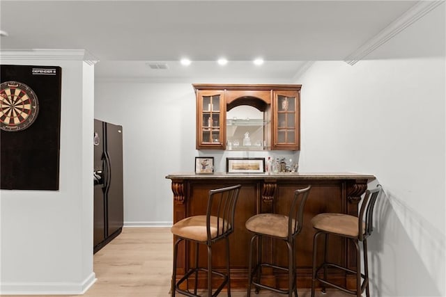 bar with black fridge with ice dispenser, light hardwood / wood-style floors, and ornamental molding