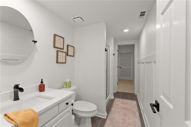 bathroom featuring tile patterned floors, vanity, toilet, and a shower with shower door