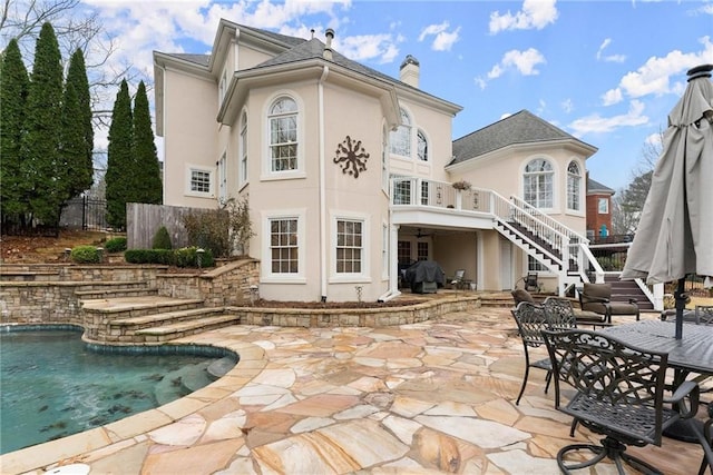 rear view of property with a fenced in pool and a patio area