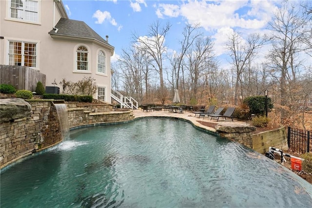 view of swimming pool featuring pool water feature, central AC unit, and a patio area