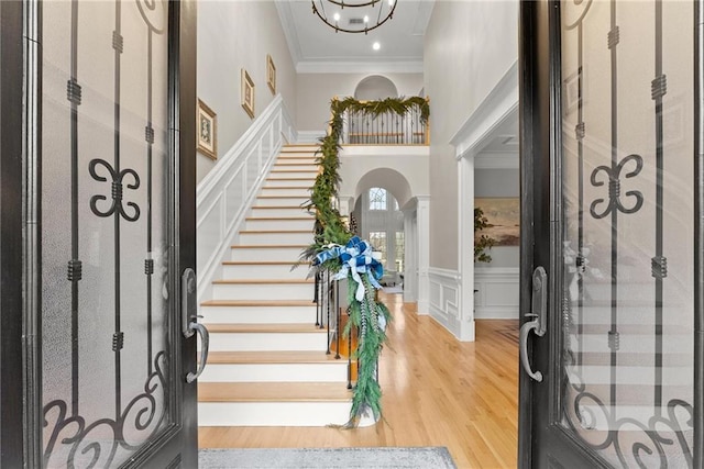 entryway featuring crown molding, wood-type flooring, and an inviting chandelier