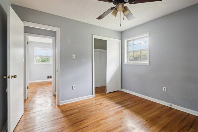 unfurnished bedroom featuring a closet, light hardwood / wood-style flooring, multiple windows, and ceiling fan