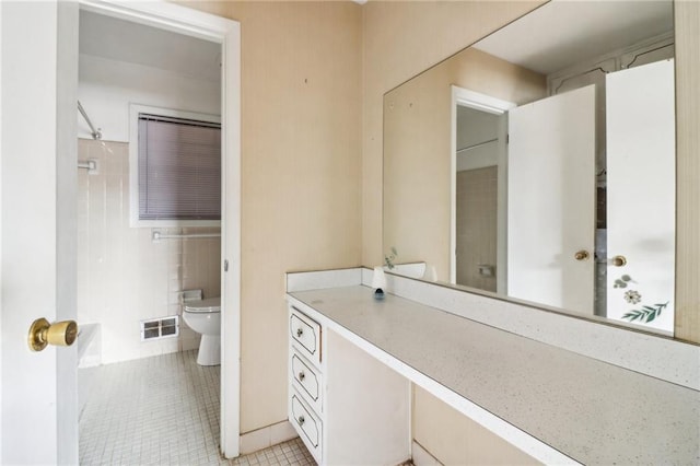 bathroom with toilet, vanity, tile patterned floors, and tile walls