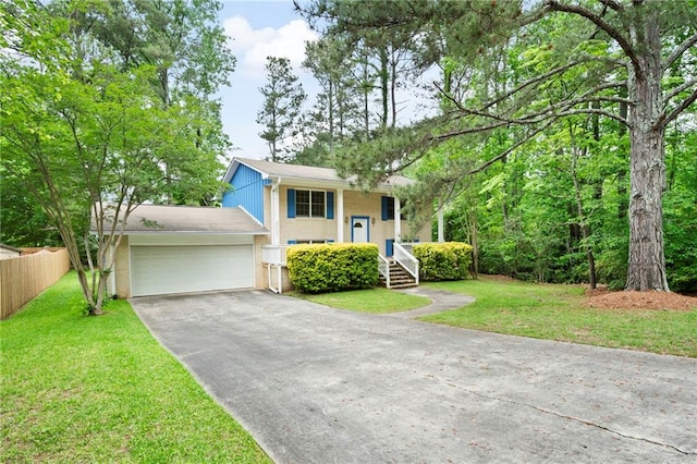 raised ranch featuring a garage, fence, driveway, and a front yard