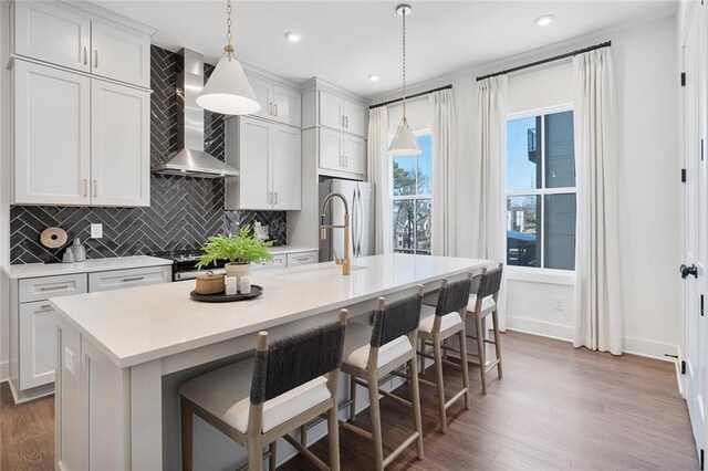 1427 Hazy Way Unit 310, Atlanta, GA 30315 - kitchen with wall chimney exhaust hood, a sink, a center island with sink, tasteful backsplash, and light countertops