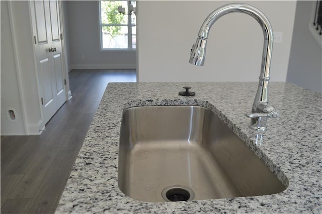 room details featuring light stone counters, dark wood-type flooring, and sink