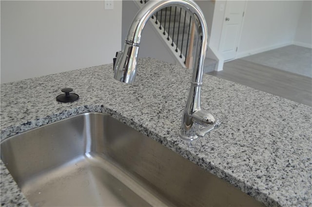 details featuring sink, light stone countertops, and wood-type flooring