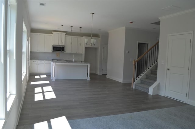 kitchen featuring white cabinets, a kitchen island with sink, dark wood-type flooring, sink, and decorative light fixtures