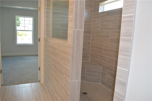 bathroom with a tile shower and tile patterned flooring