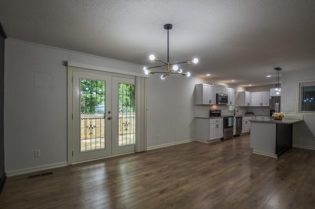 5640 Redan Cir, Stone Mountain, GA 30088 - kitchen with stainless steel appliances, a chandelier, a textured ceiling, dark wood-style floors, and baseboards