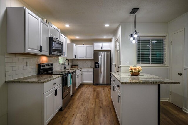 5640 Redan Cir, Stone Mountain, GA 30088 - kitchen featuring appliances with stainless steel finishes, a kitchen island, a sink, dark wood-style flooring, and light stone countertops