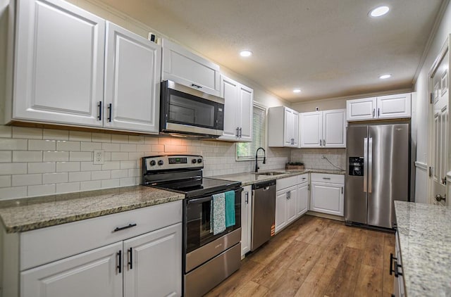 5640 Redan Cir, Stone Mountain, GA 30088 - kitchen with appliances with stainless steel finishes, a sink, white cabinetry, light wood-style floors, and light stone counters