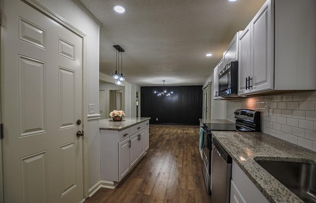 5640 Redan Cir, Stone Mountain, GA 30088 - kitchen featuring stainless steel appliances, a textured ceiling, backsplash, dark wood-style flooring, and hanging light fixtures