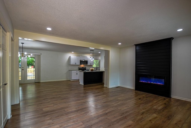 5640 Redan Cir, Stone Mountain, GA 30088 - unfurnished living room with a textured ceiling, dark wood-style floors, baseboards, recessed lighting, and a fireplace