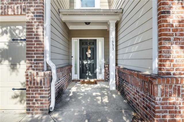 doorway to property with a garage and brick siding