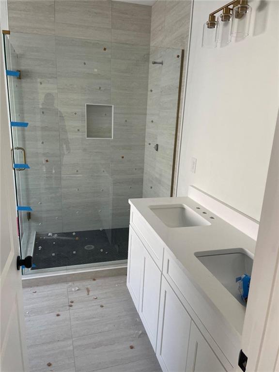 bathroom with tiled shower and vanity