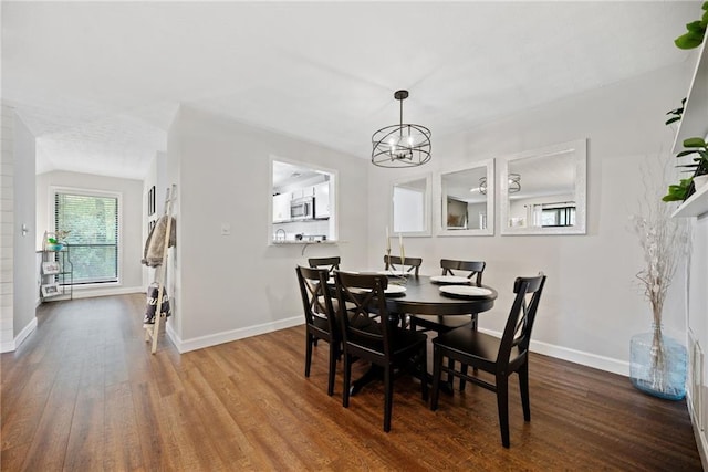 dining area with hardwood / wood-style floors, a notable chandelier, and a fireplace