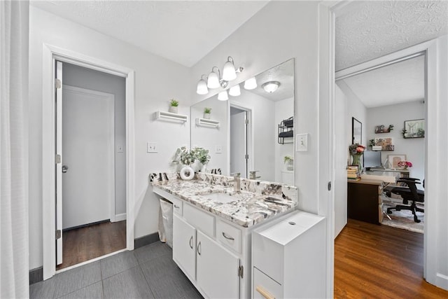 bathroom with hardwood / wood-style floors, vanity, and a textured ceiling