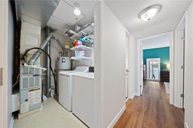 laundry area with washing machine and clothes dryer, wood-type flooring, and gas water heater