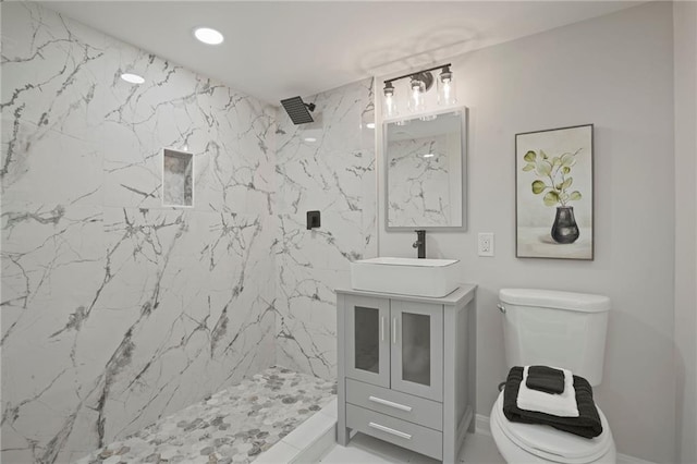 bathroom with a tile shower, vanity, and toilet