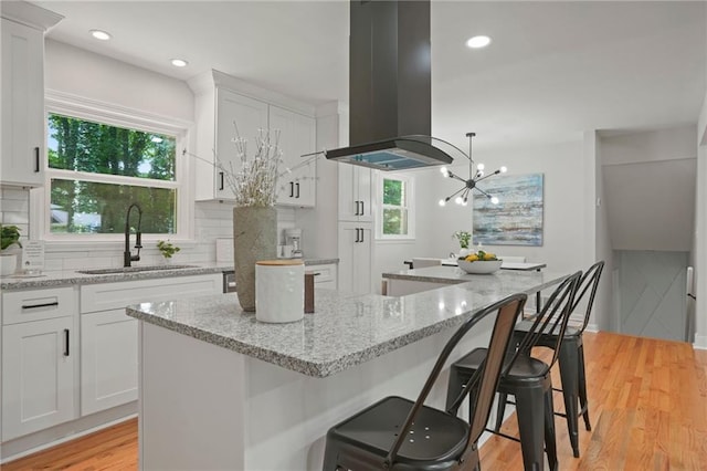 kitchen featuring sink, white cabinetry, and island exhaust hood