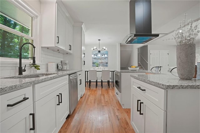 kitchen featuring a chandelier, extractor fan, sink, white cabinetry, and light stone countertops