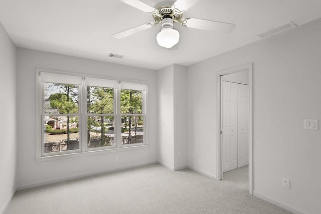 carpeted spare room featuring ceiling fan