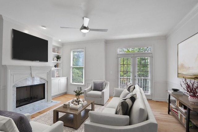 living room featuring a fireplace, built in features, light hardwood / wood-style floors, and a healthy amount of sunlight