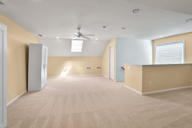 interior space featuring light carpet, ceiling fan, lofted ceiling with skylight, and a healthy amount of sunlight