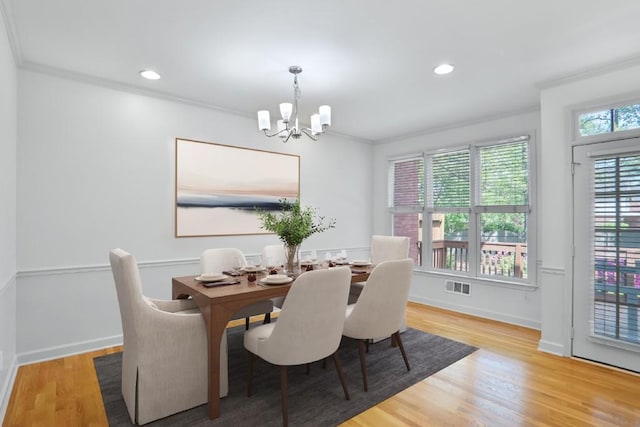 dining space featuring light hardwood / wood-style flooring, a chandelier, and ornamental molding