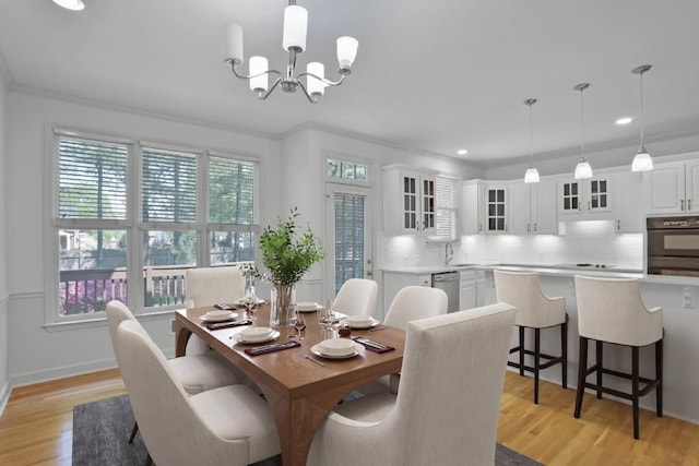 dining room with ornamental molding, sink, an inviting chandelier, and light hardwood / wood-style flooring