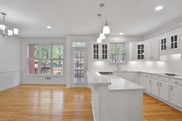 kitchen featuring decorative light fixtures, stovetop, light hardwood / wood-style flooring, and white cabinetry