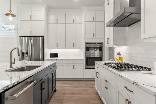 228 Idylwilde Way, Canton, GA 30115 - kitchen with hanging light fixtures, a sink, wall chimney range hood, appliances with stainless steel finishes, and white cabinetry