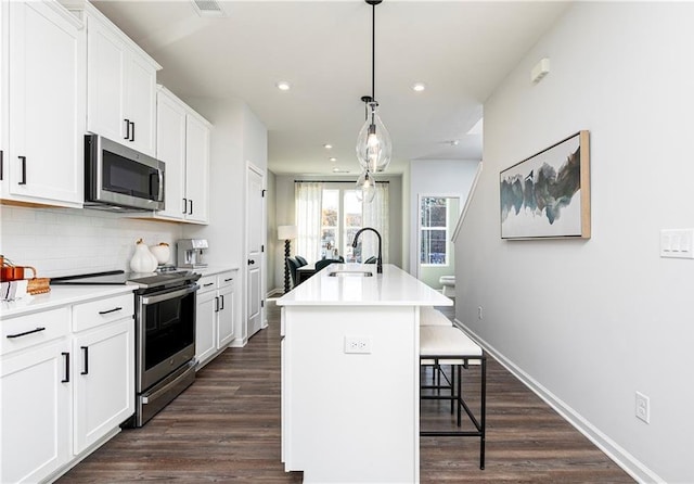 339 Skylar Way SE, Atlanta, GA 30315 - kitchen with stainless steel appliances, a sink, backsplash, dark wood-type flooring, and a breakfast bar area