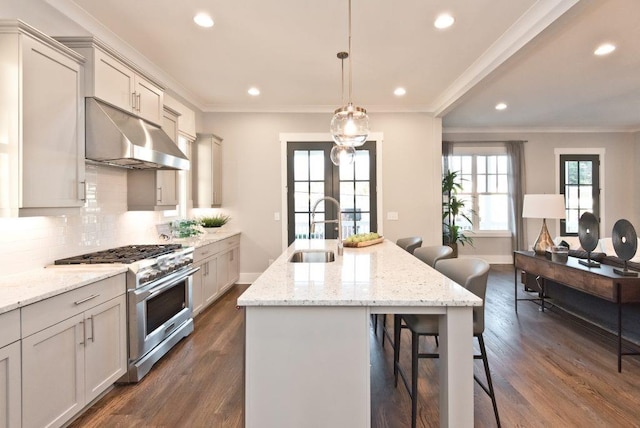 kitchen featuring a kitchen bar, stainless steel range, a kitchen island with sink, ornamental molding, and sink