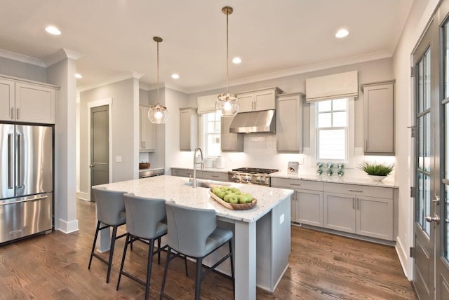 kitchen featuring light stone countertops, pendant lighting, sink, a center island with sink, and high end refrigerator