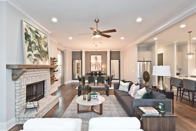 living room featuring dark wood-type flooring, ornamental molding, a fireplace, and ceiling fan