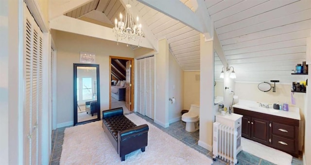 bathroom featuring lofted ceiling with beams, toilet, radiator heating unit, vanity, and baseboards