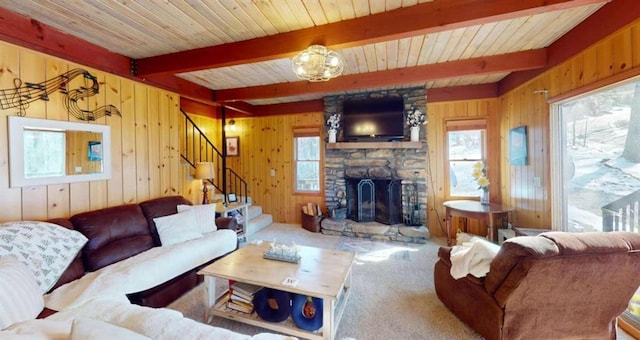 carpeted living area featuring a healthy amount of sunlight, a fireplace, beamed ceiling, and stairs