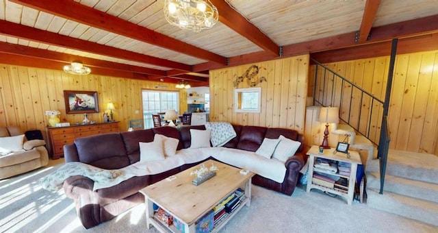 living room featuring stairway, carpet floors, wood walls, a chandelier, and beam ceiling