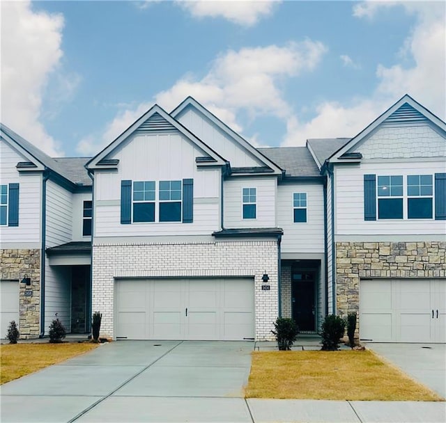 view of front of home with a garage, driveway, brick siding, and board and batten siding