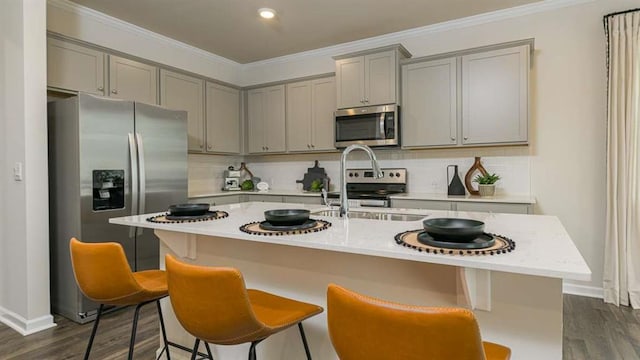 kitchen featuring tasteful backsplash, appliances with stainless steel finishes, ornamental molding, and gray cabinetry