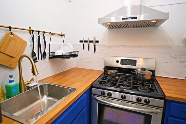 kitchen featuring blue cabinetry, island range hood, sink, and stainless steel gas range