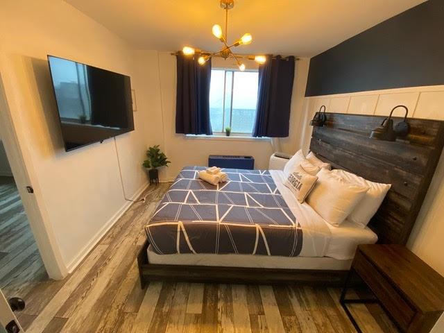 bedroom featuring a chandelier, vaulted ceiling, and hardwood / wood-style flooring