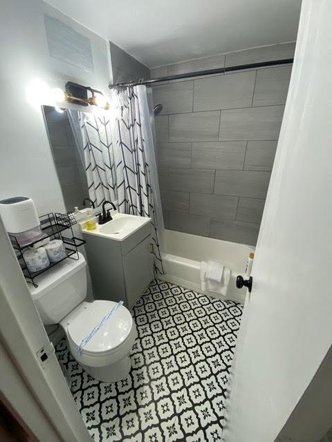 full bathroom with shower / bath combo with shower curtain, vanity, and toilet