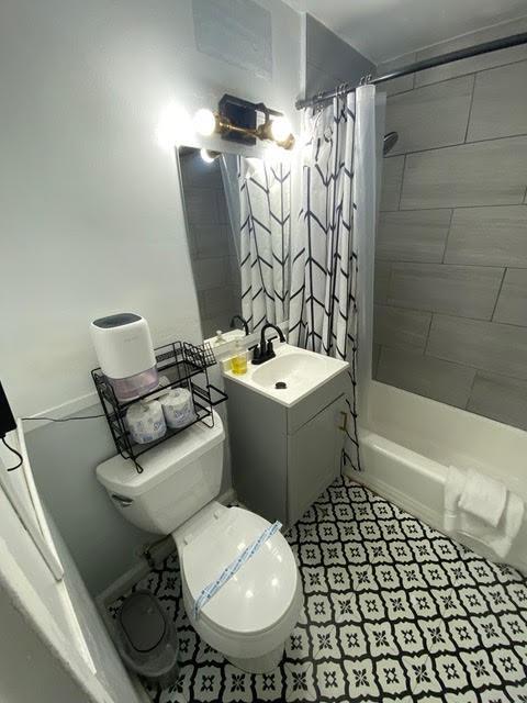 full bathroom featuring vanity, shower / bath combo, and toilet