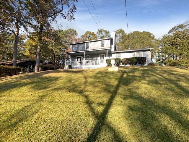 rear view of house featuring a lawn and covered porch