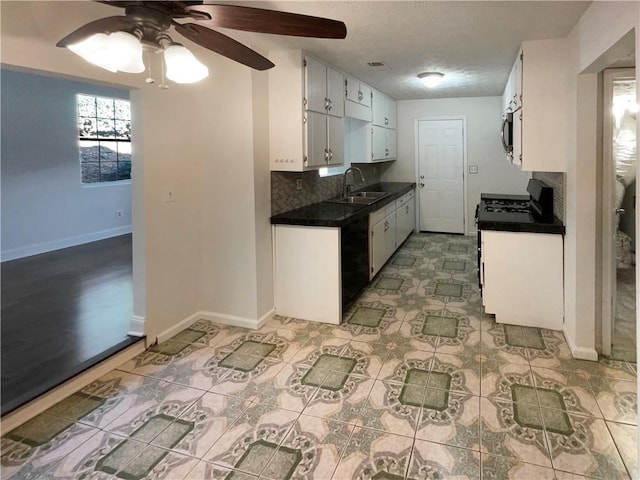 kitchen with stove, white cabinets, sink, ceiling fan, and tasteful backsplash