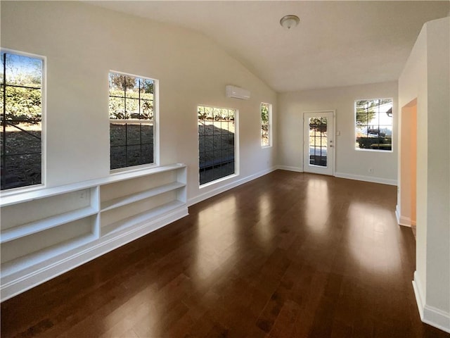 unfurnished living room featuring a wall mounted AC, a wealth of natural light, and dark hardwood / wood-style floors